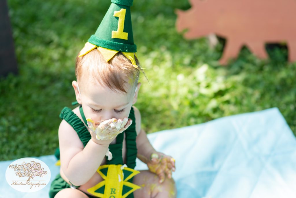Little boy eats one year old birthday cake during pictures by syracuse family photographer