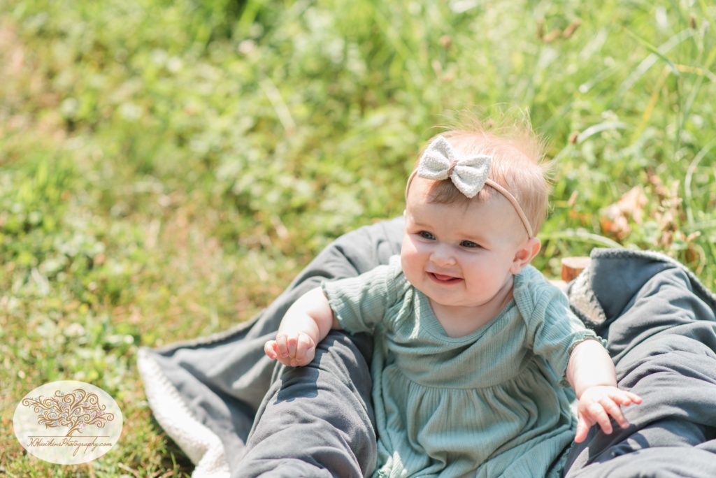Baby smiles during her pictures session in a wheat field while sitting in a box