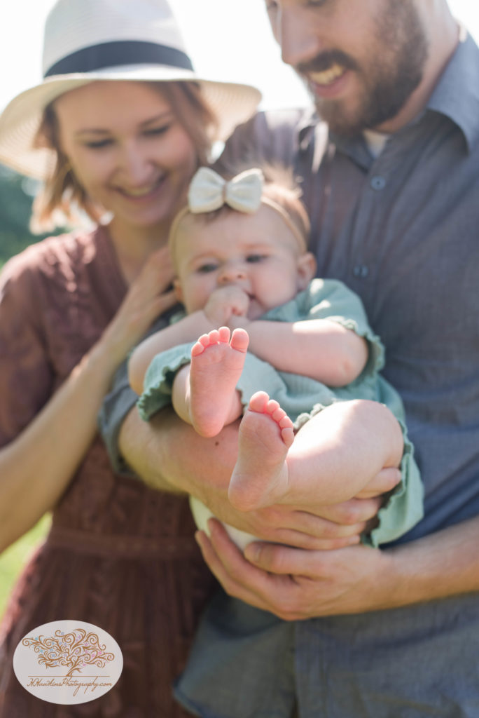Baby feet in focus with mom and dad in the background during syracuse summer family pictures