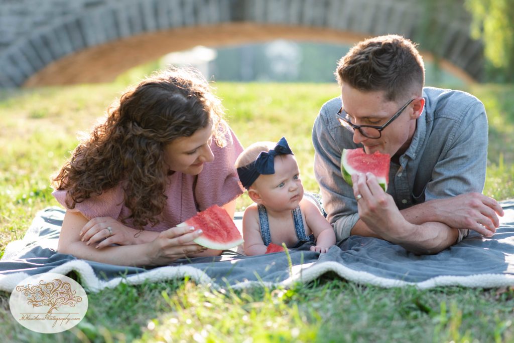 Syracuse NY family eats watermelon with their baby during family pictures while photographer captures memories
