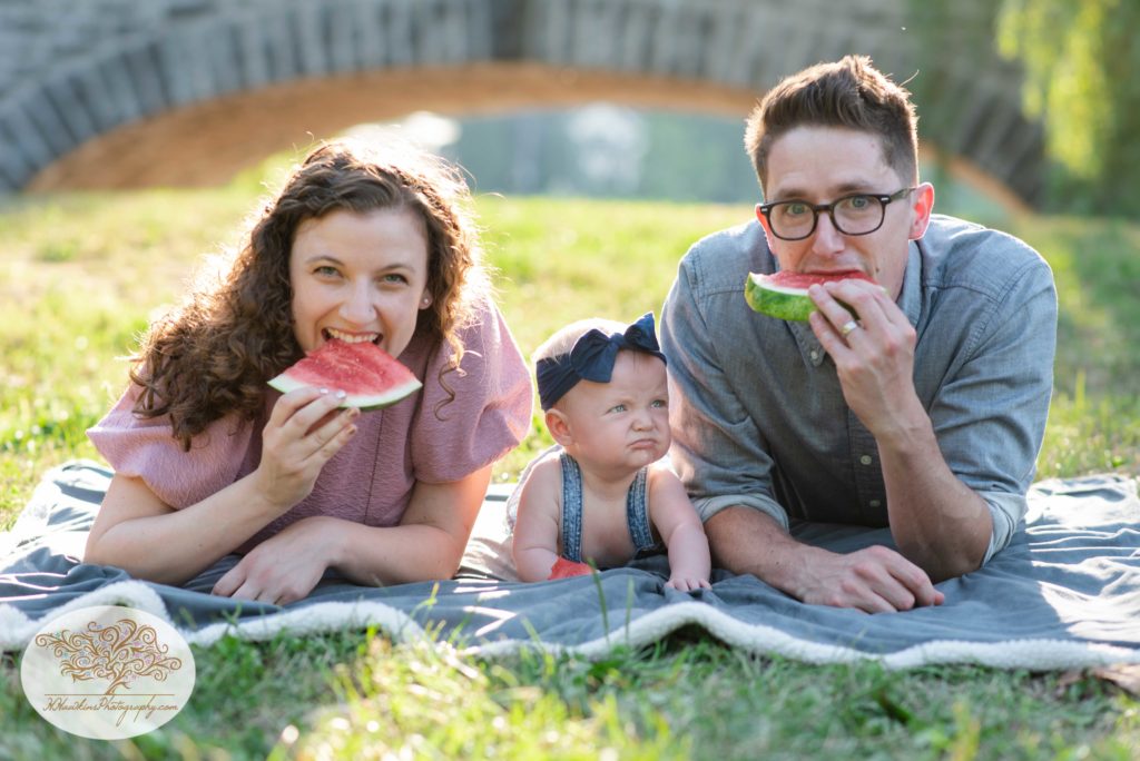 Syracuse NY family eats watermelon with their baby during family pictures while photographer captures memories
