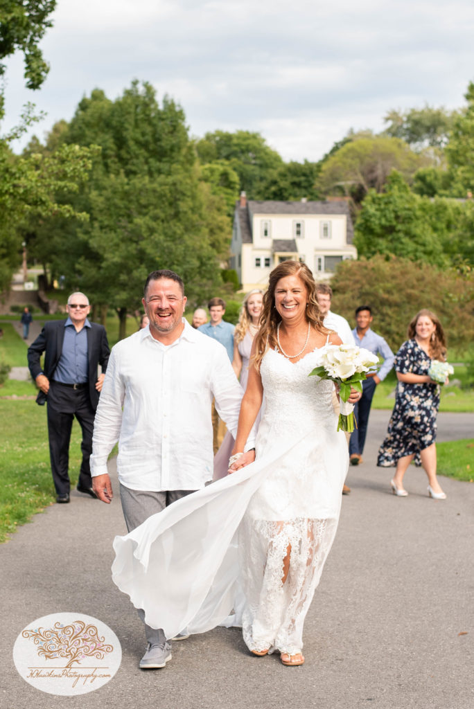 Bride and groom walk in front of their bridal party down path at Hoopes Park in Auburn NY by Fingerlakes Wedding photogrpaher