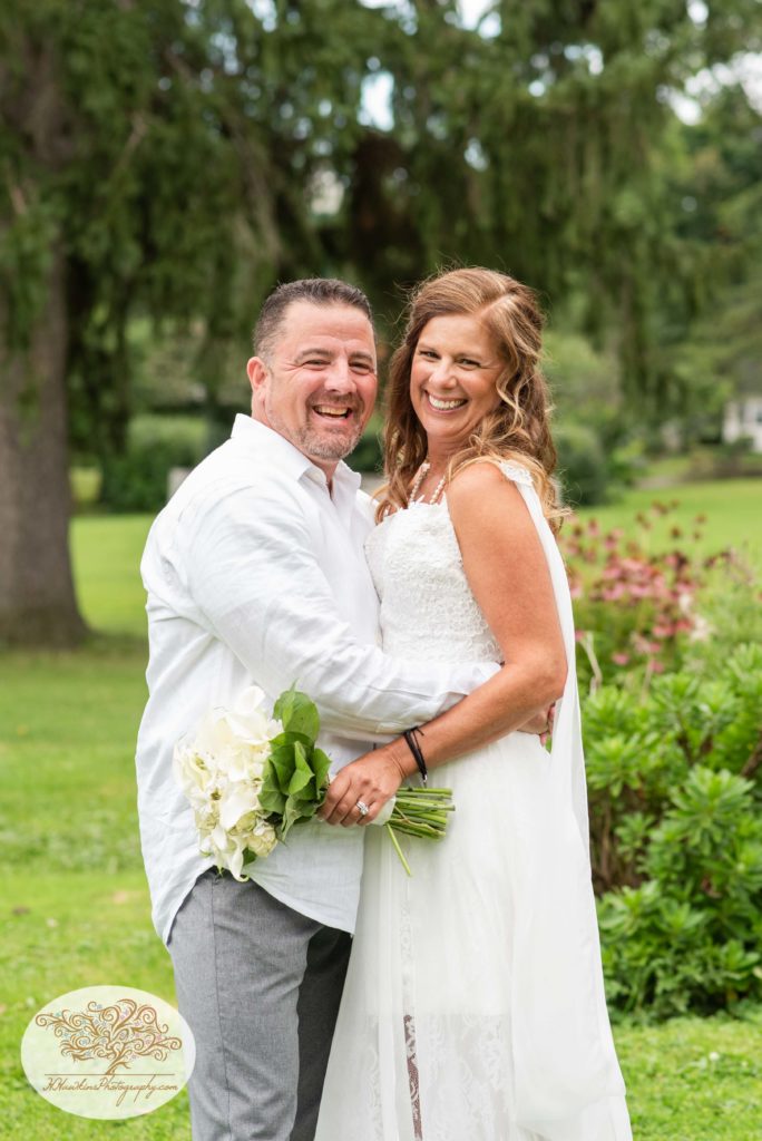 Bride and groom smile at the camera as they stand in Hoopes Park in Auburn NY captured by Fingerlakes wedding photographer
