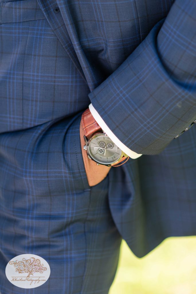 Groom's hand in the pocket of his navy blue suit and watch on his wrist