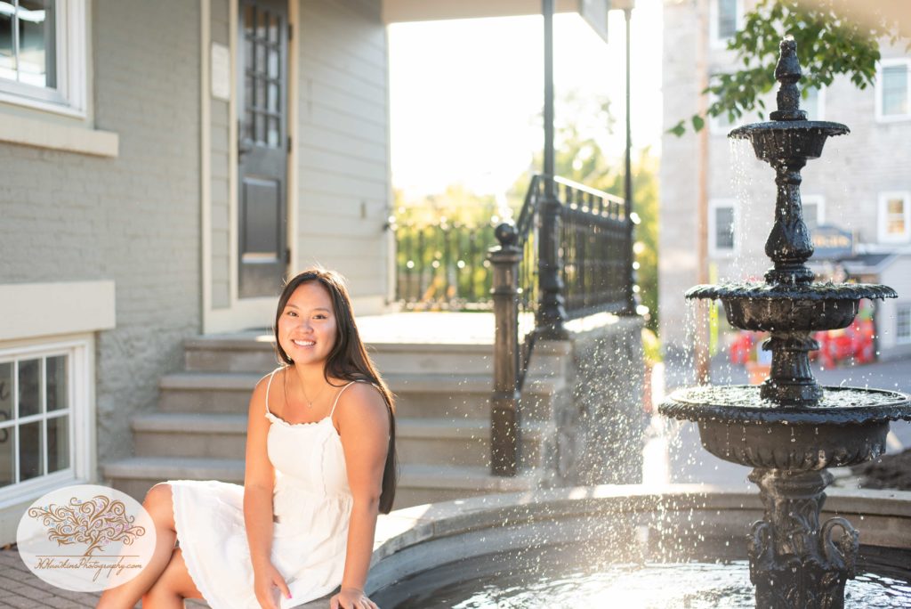 High school senior sits at fountain in the Village of Skaneateles for her portrait session by Syracuse Photographer