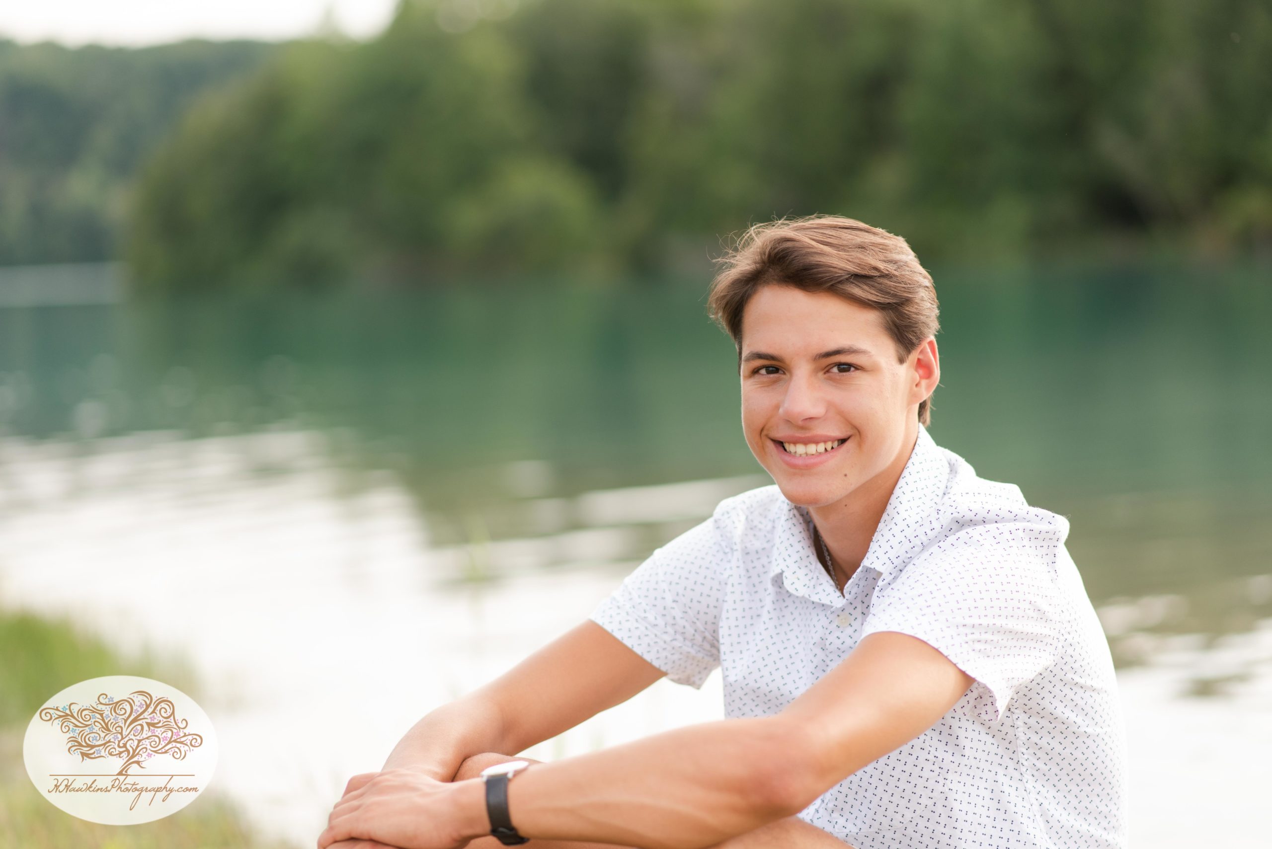 High school boy poses by sitting for his senior pictures at Green Lakes State Park