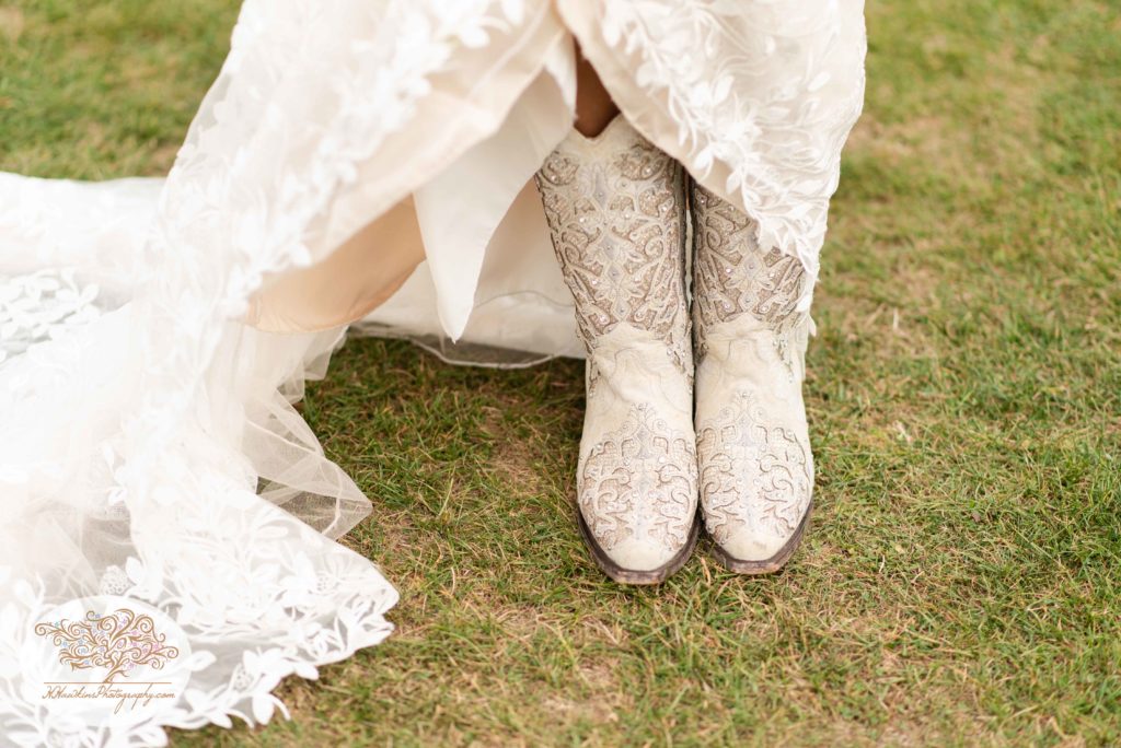 Bride shows off her white cowgirl boots and lace wedding dress