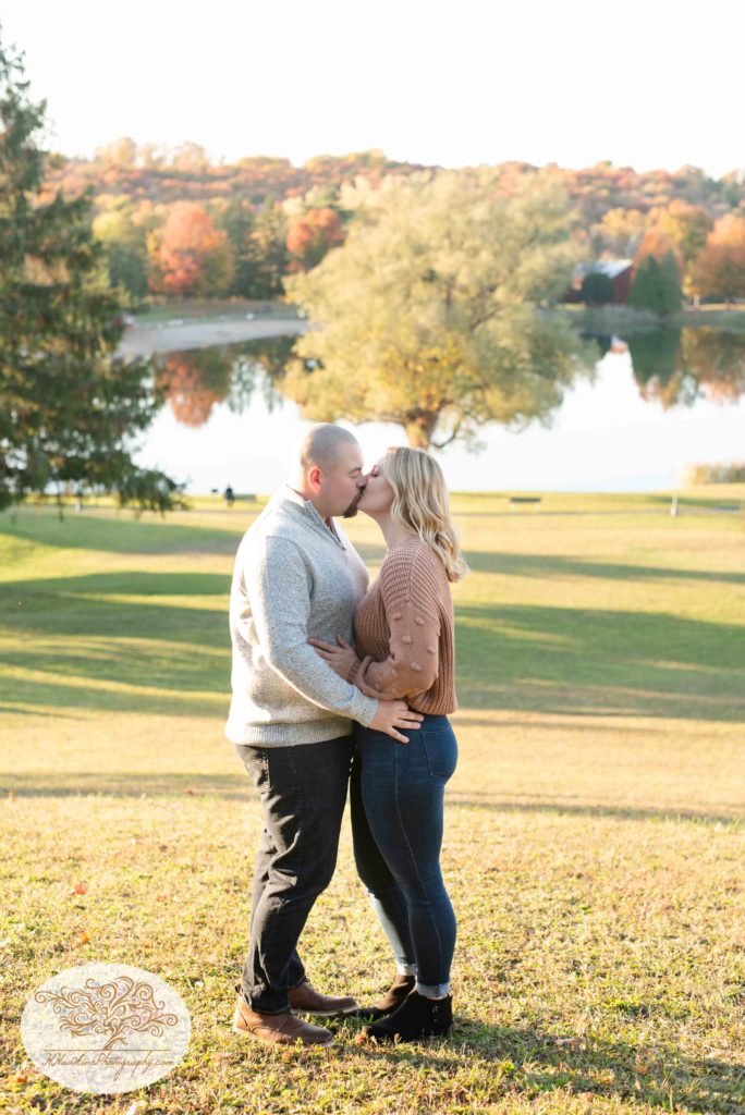 Bride and groom to be kiss in front of Gillie Lake in Camillus NY after he surprised her with proposal by Syracuse wedding photographer