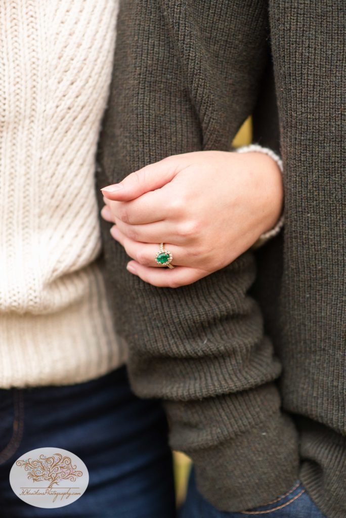 Bride shows off her emerald engagement ring as she holds onto her groom's arm