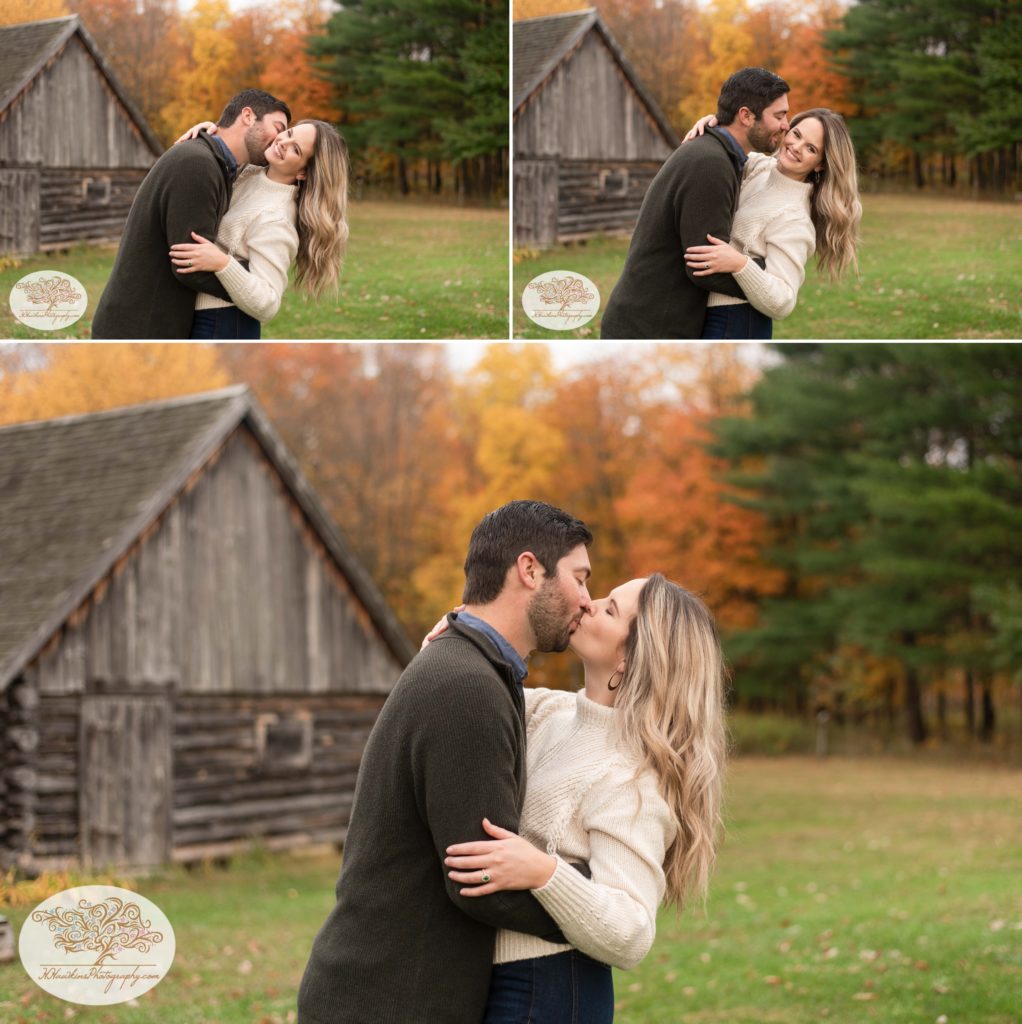 Bride and groom kiss in front of autumn foliage and log cabin at Baltimore woods in Marcellus NY for their Syracuse fall engagement pictures