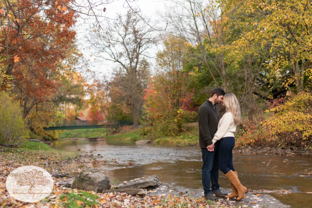 Bride and groom stand out on a rock in the creek at Marcellus Park for their Syracuse fall engagement pictures