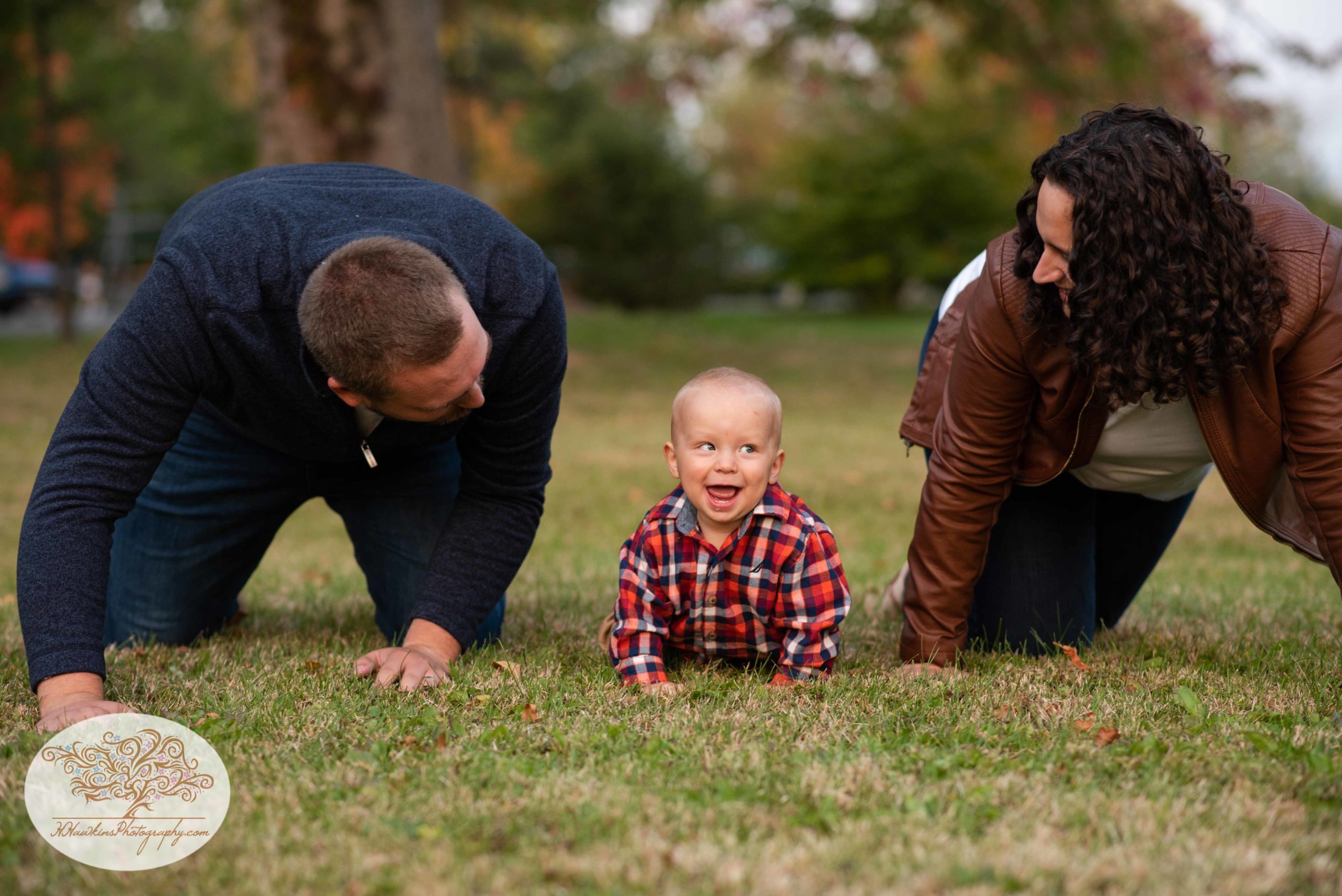 mom and dad crawl on the ground with their little boy during their Syracuse NY fall family pictures