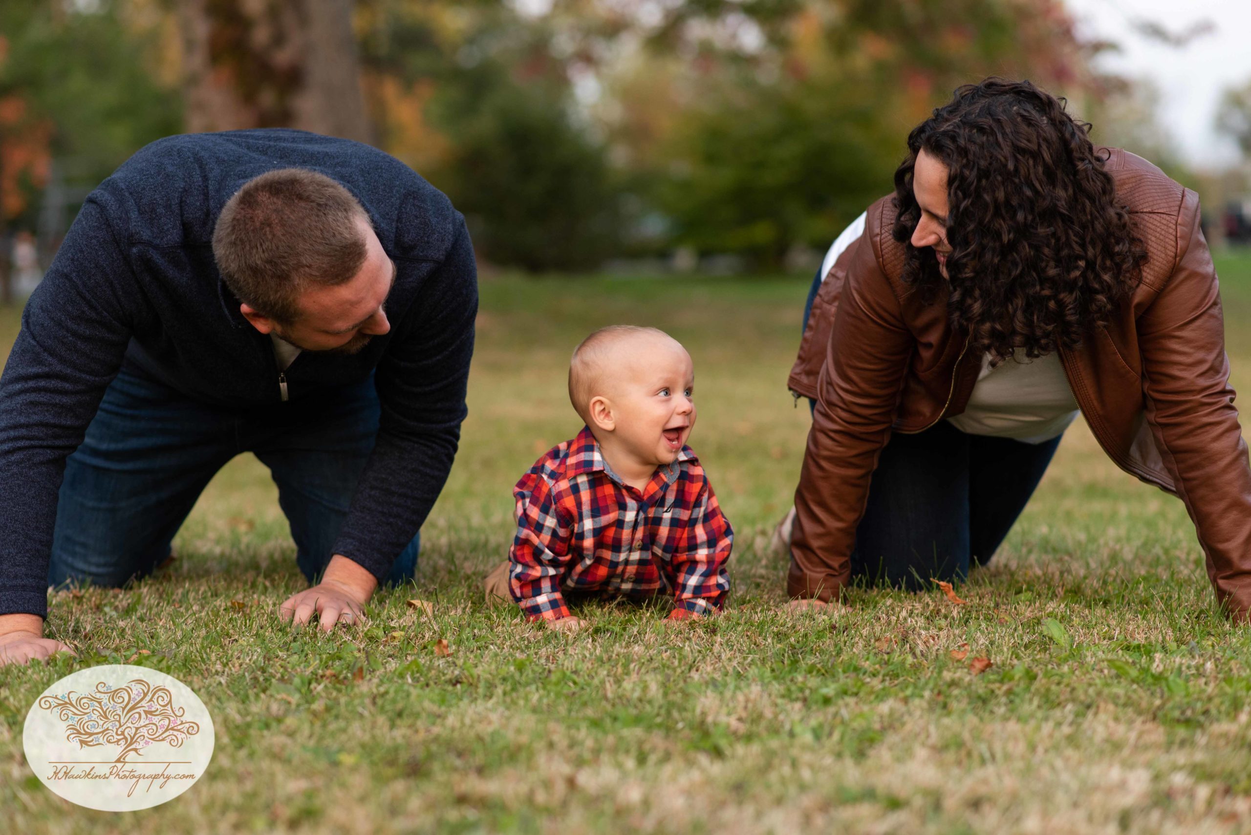 mom and dad crawl on the ground with their little boy during their Syracuse NY fall family pictures