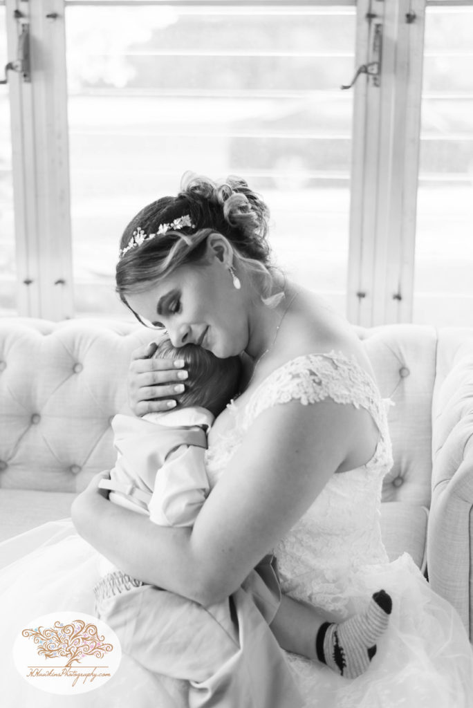 Bride snuggles her son the ring bearer in her wedding dress