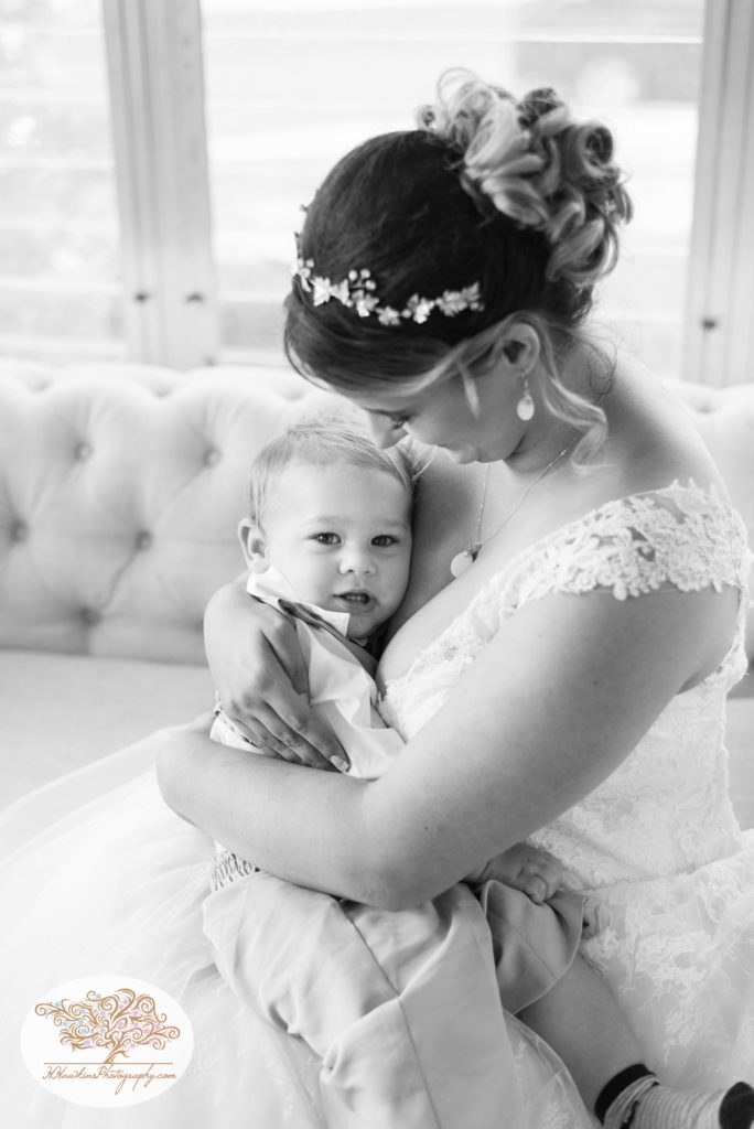 Bride snuggles her son the ring bearer in her wedding dress