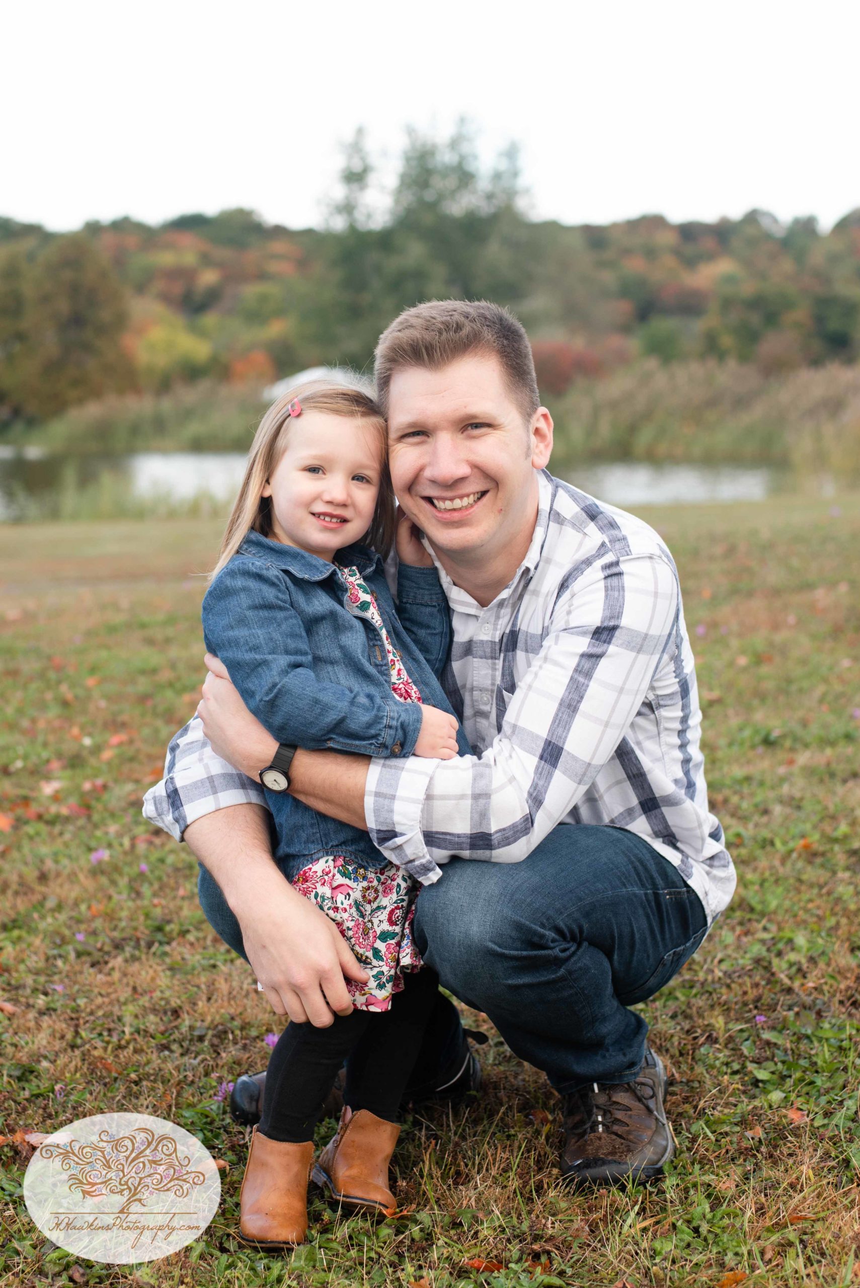 Dad squats down to hug his little girl for family pictures