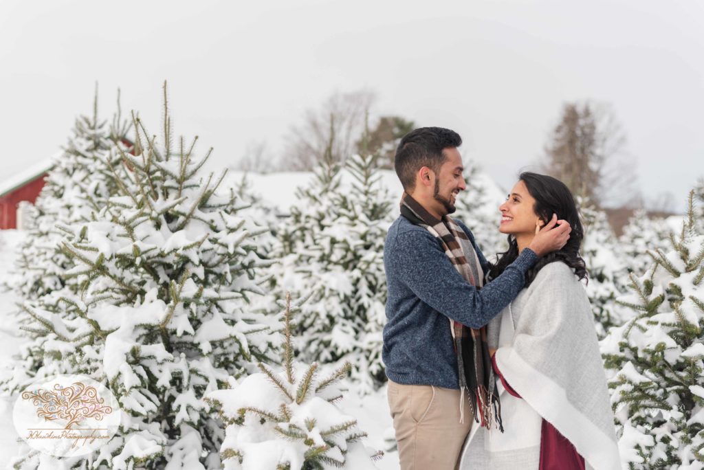 Groom to be tucks bride's hair behind her ear during snowy engagement session at Critz Farms in Cazenovia NY