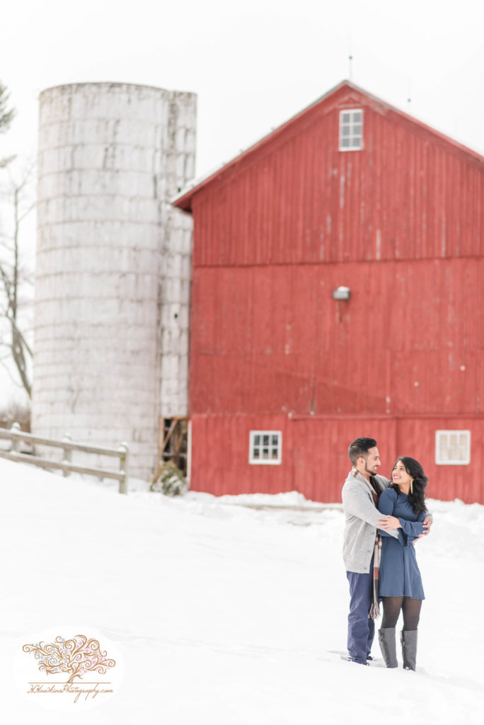 Snowy engagement pictures at Critz Farms in Cazenovia for engaged couple in front of red barn