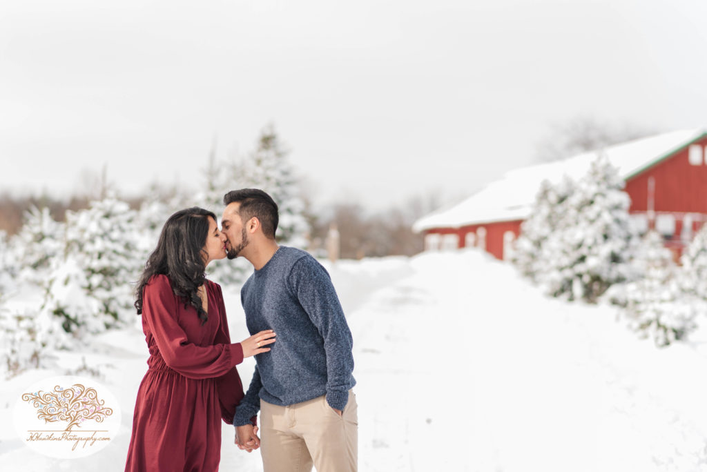 Bride and groom walk away from barn at Critz Farms during their snowy engagement pictures in Cazenovia NY