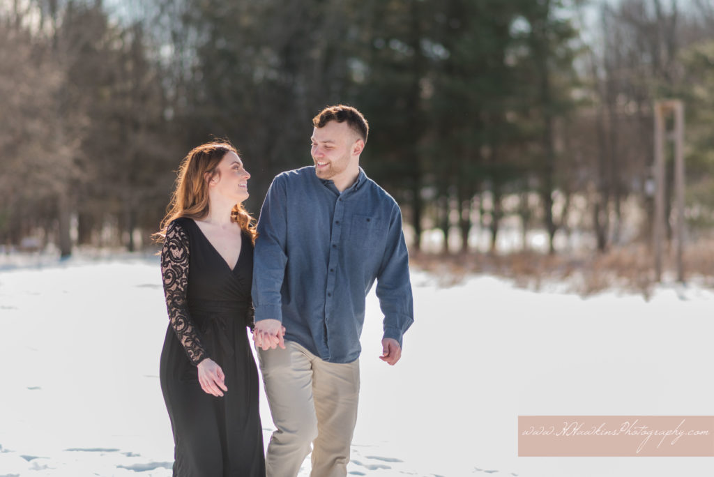 Bride and groom walk together through the snow at Baltimore Woods Marcellus NY for their engagement pictures by Syracuse wedding photographer