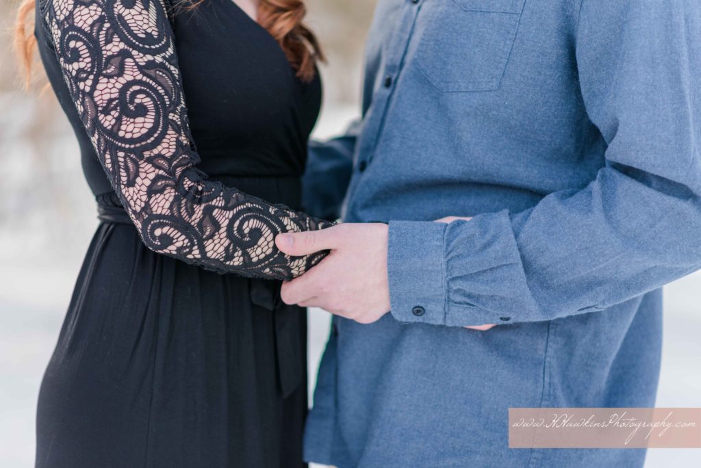 Detail picture of bride in black lace sleeves and groom in jean shirt holding each other's hands during engagement pictures in Syracuse NY