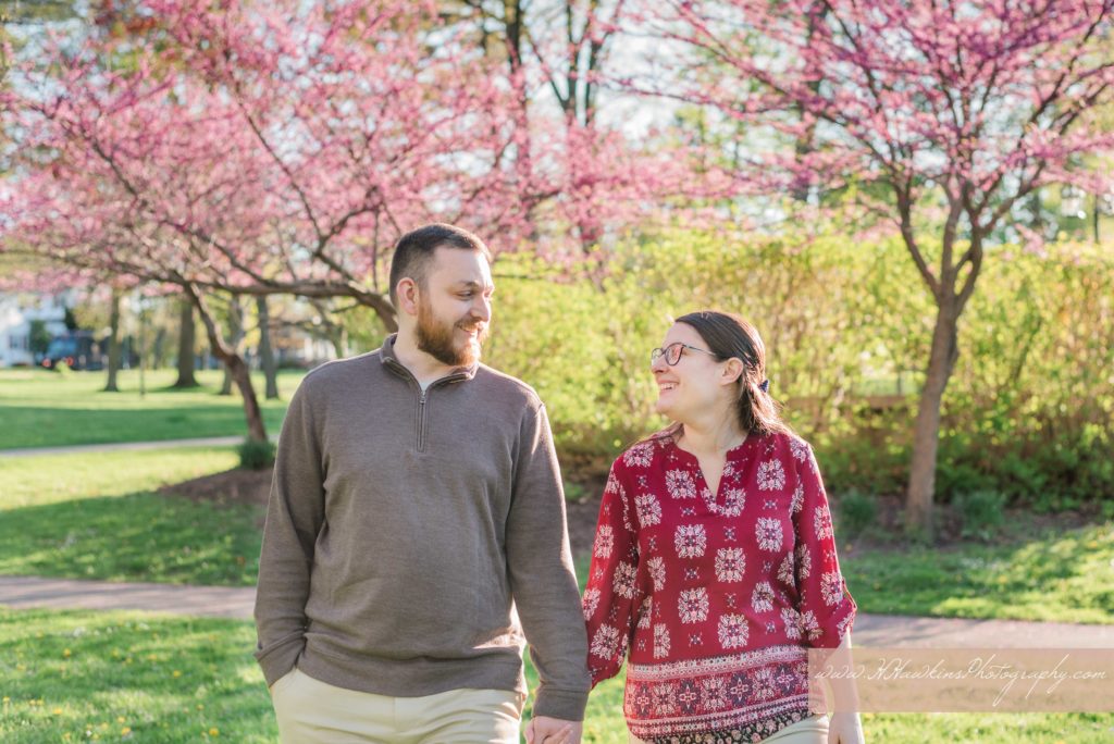 Newly engaged couple stands in front of purple blossoming tree in the spring at Hoopes Park in Auburn NY