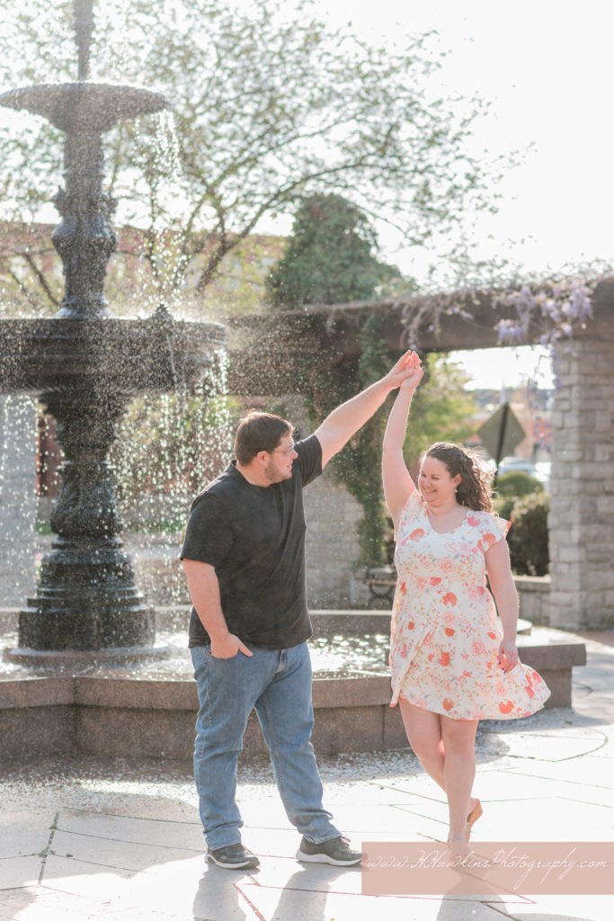 Groom spins bride in front of fountain at Franklin Square Park in Syracuse NY