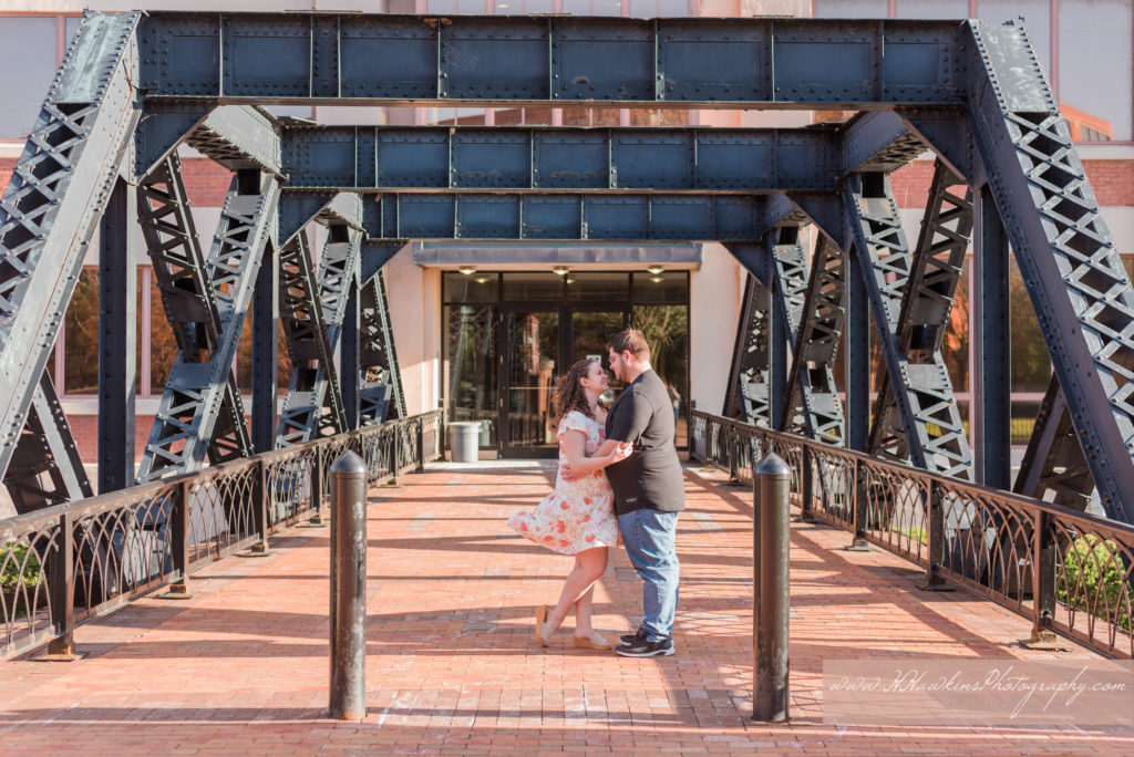 Bride and groom stand underneath an industrial bridge at Creek Walk Franklin Square Park in Syracuse NY