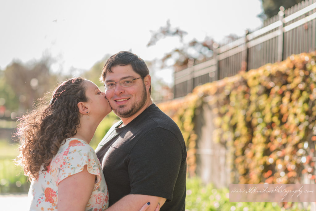 Bride kisses groom on the cheek at the Creekwalk in Syracuse NY during their engagement pictures by Syracuse wedding photographer