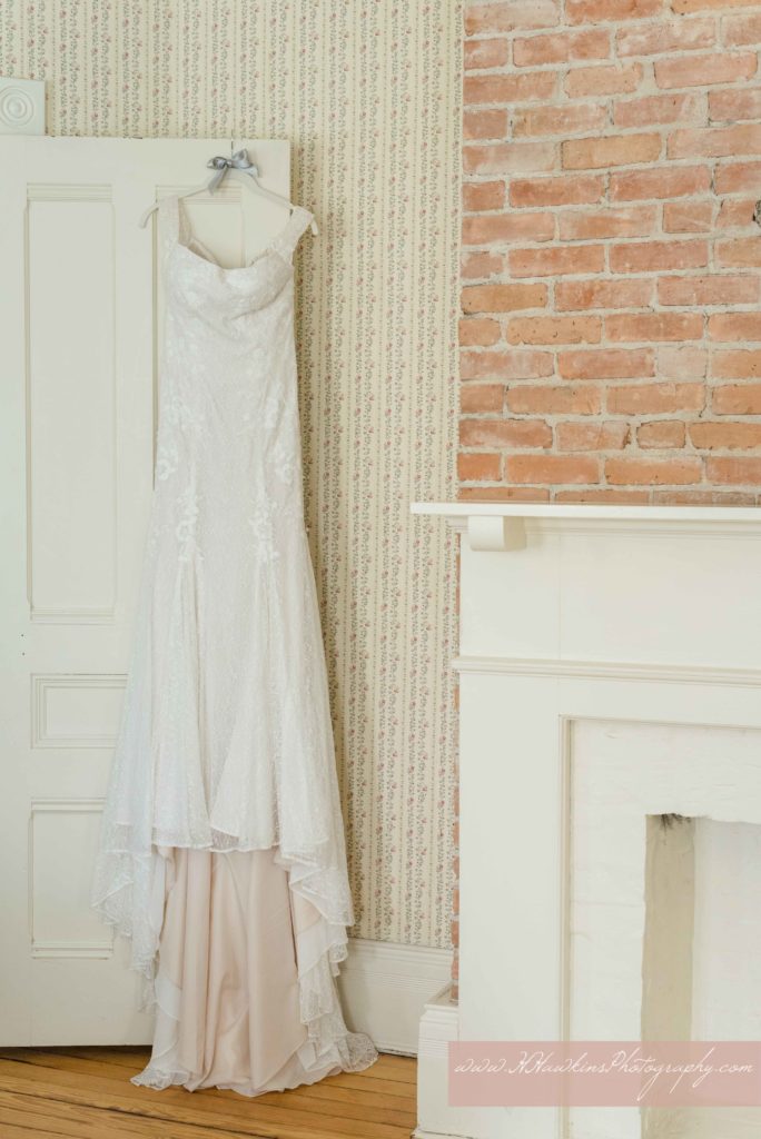 White lace wedding dress hanging at the Springside Inn beside old fireplace in one of their rooms
