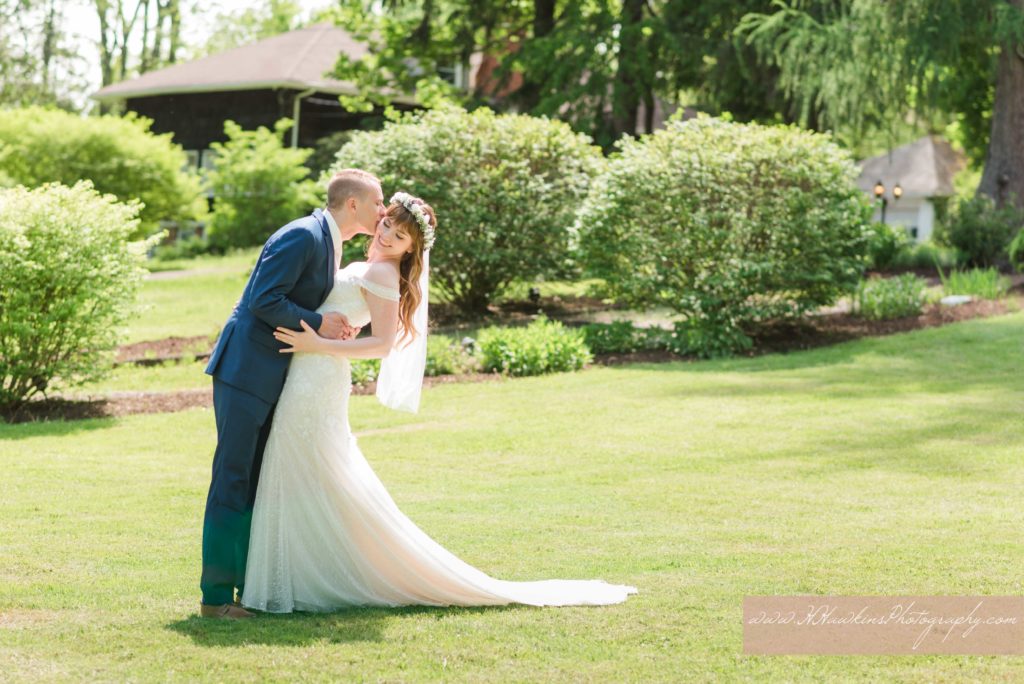 Groom kisses bride in front of Springside Inn Auburn NY on their wedding day