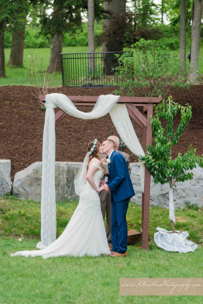 Bride and groom kiss during wedding ceremony on the back lawn of the Springside Inn in Auburn NY