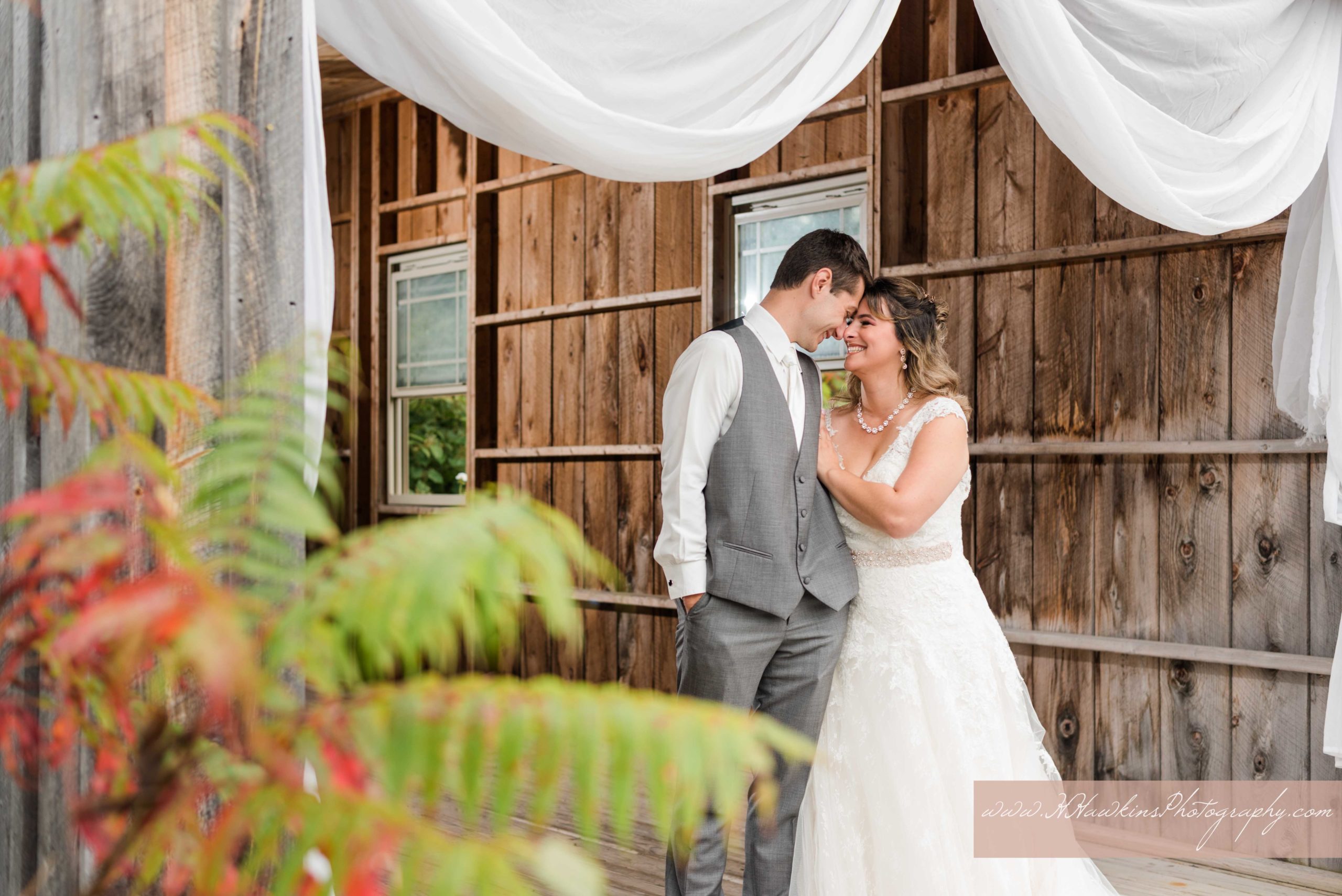 portraits of bride and groom inside Wolf Oak Acre's covered bridge during rainy wedding day