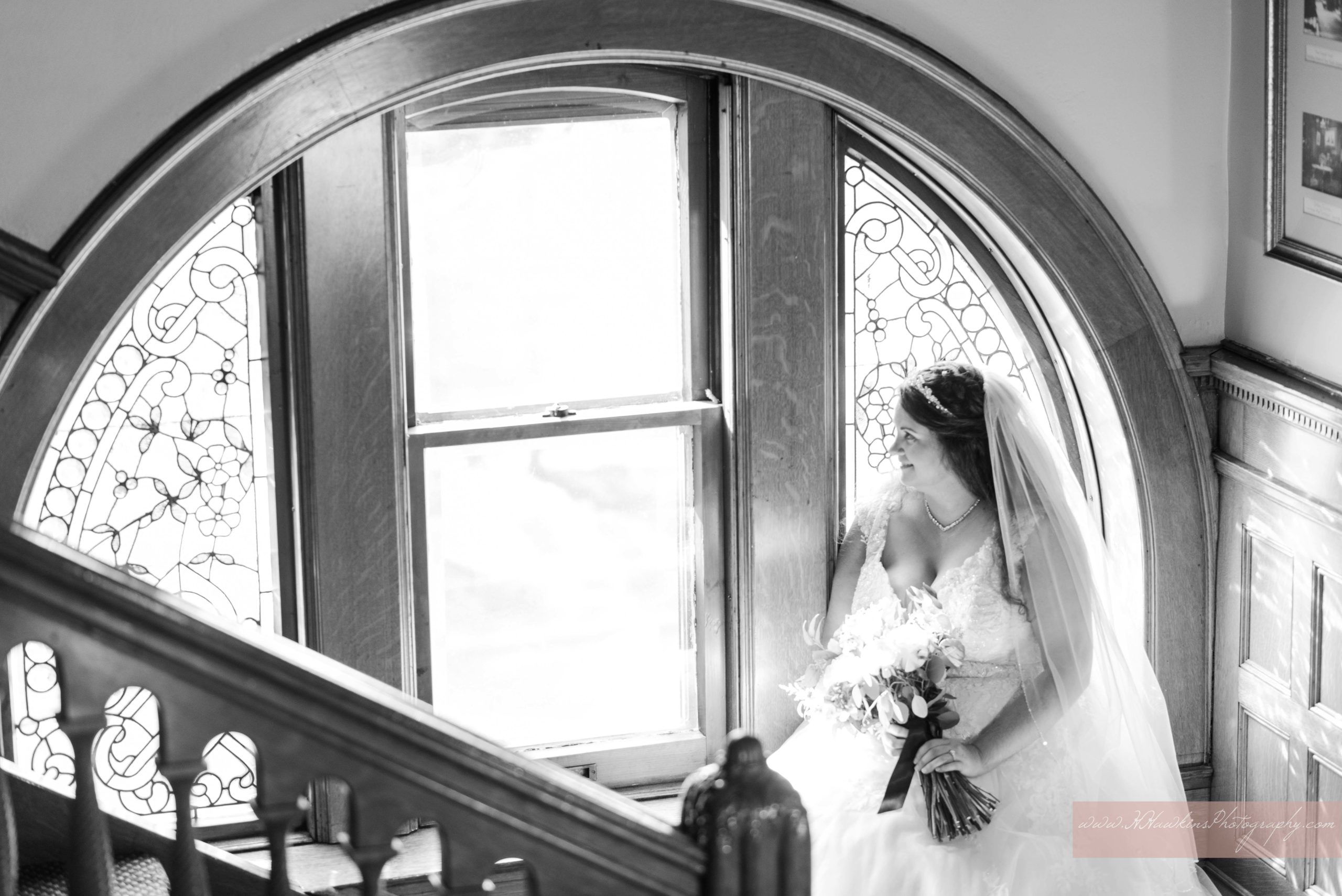 Bride looks out of rounded stained glass window at Lakeview Florida castle wedding