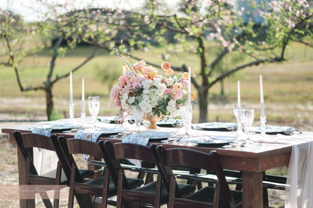 Wedding reception table with flowers by Lily's Flower Shop and set by Crystal Event Rentals and Design in Acres of Grace wedding venue peach blossom orchard