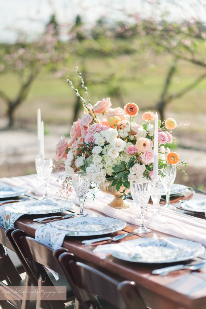 Flower centerpiece with peach and pink on reception table in Acres of Grace wedding venue peach blossom orchard