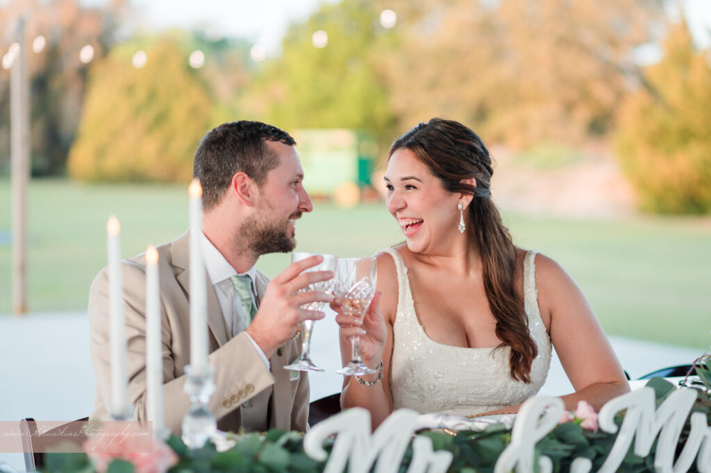 Bride and groom toast each other at Tablescape in pole barn at Acres of Grace Family Farms wedding venue in Howey in the Hills FL