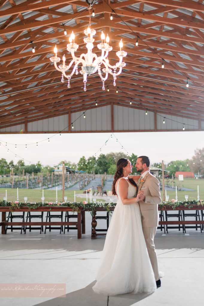 Bride and groom dance under chandelier at Acres of Grace Family Farms wedding venue in Howey in the Hills FL