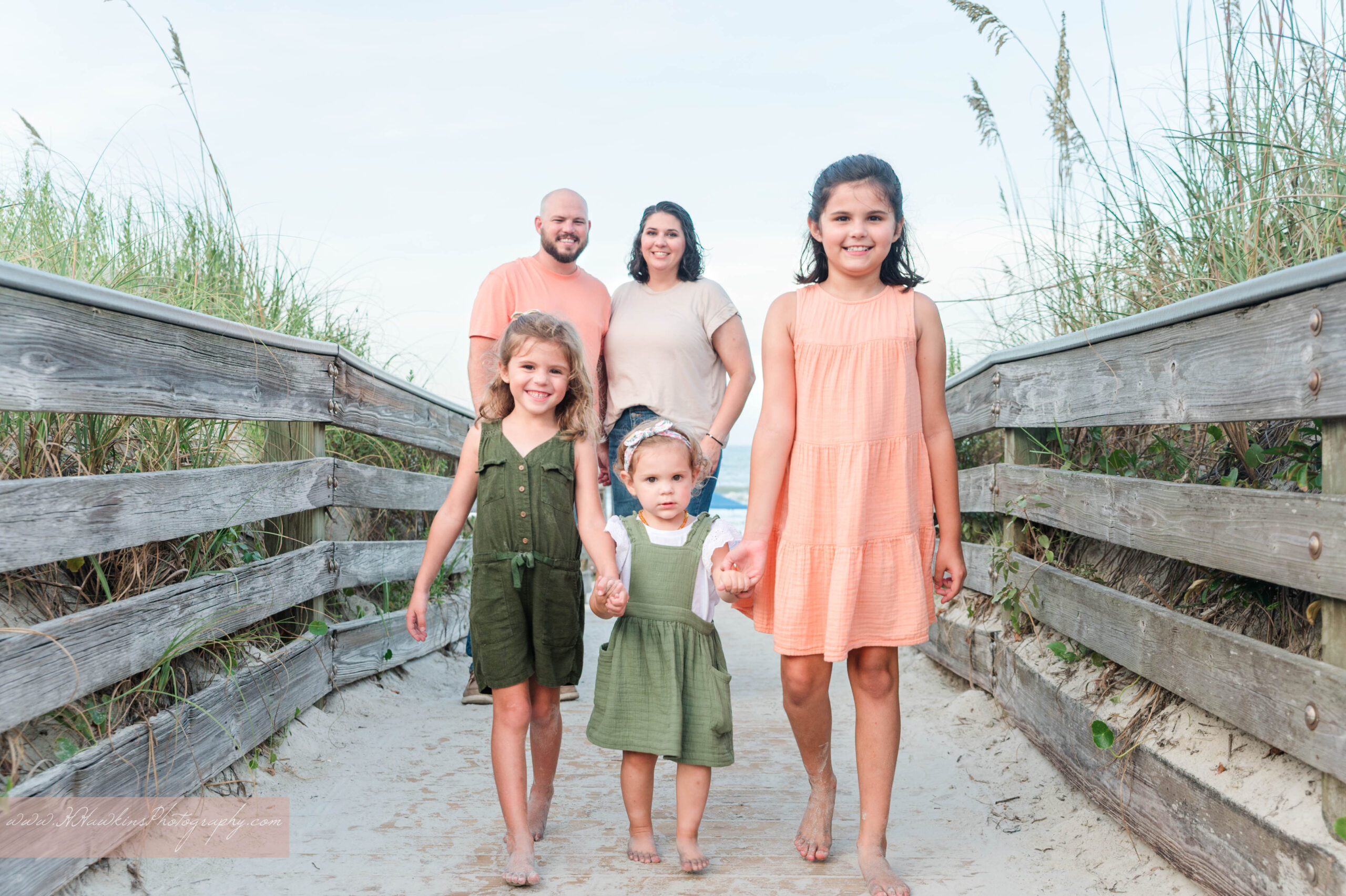 Mom, dad and girls stand on wooden walkover bridge at Grayce K Bark Family park during their New Smyrna Beach family picture session
