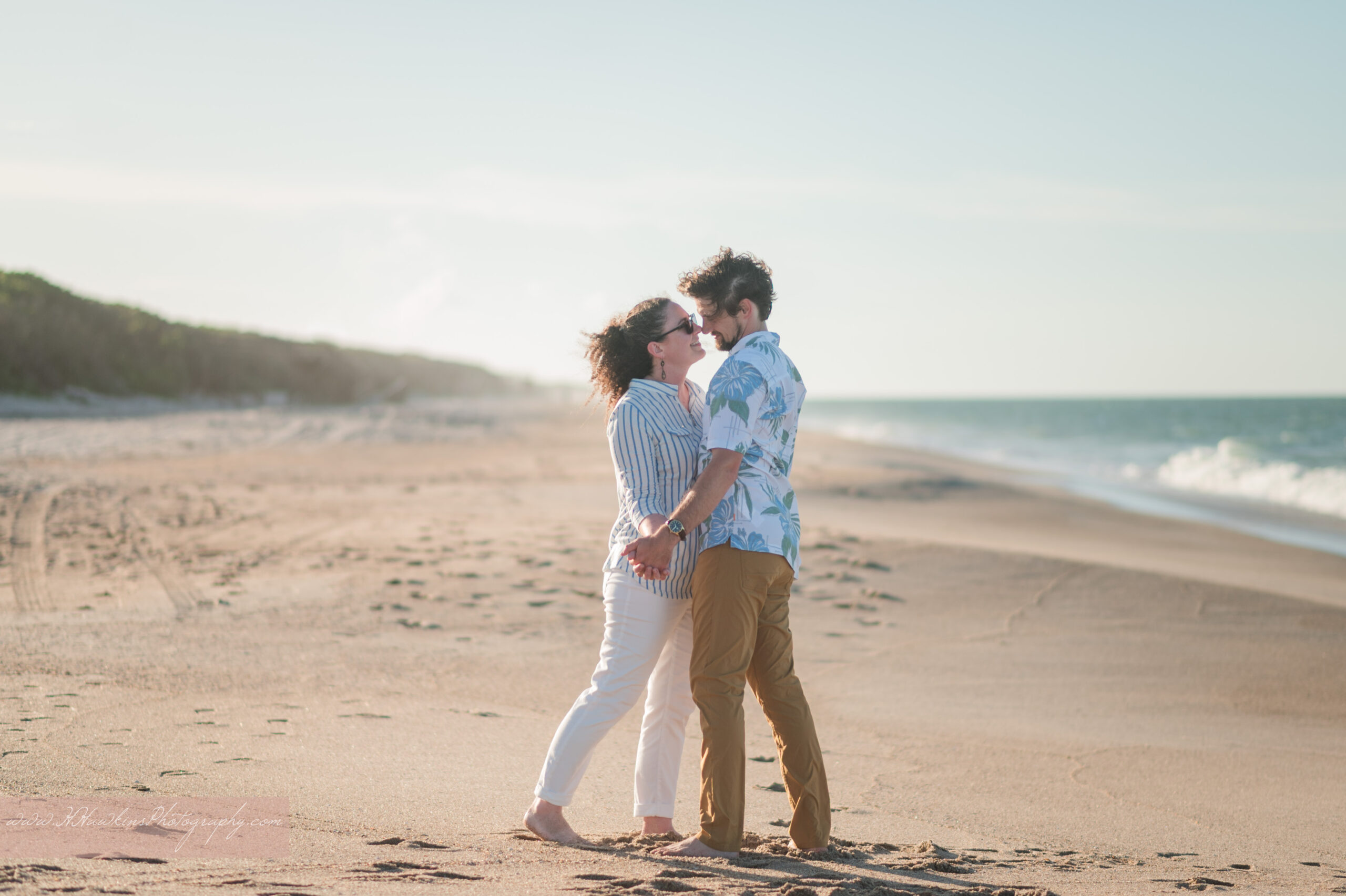 Guy and girl in an almost kiss standing on the sand of Playalinda Beach during their engagement photos session