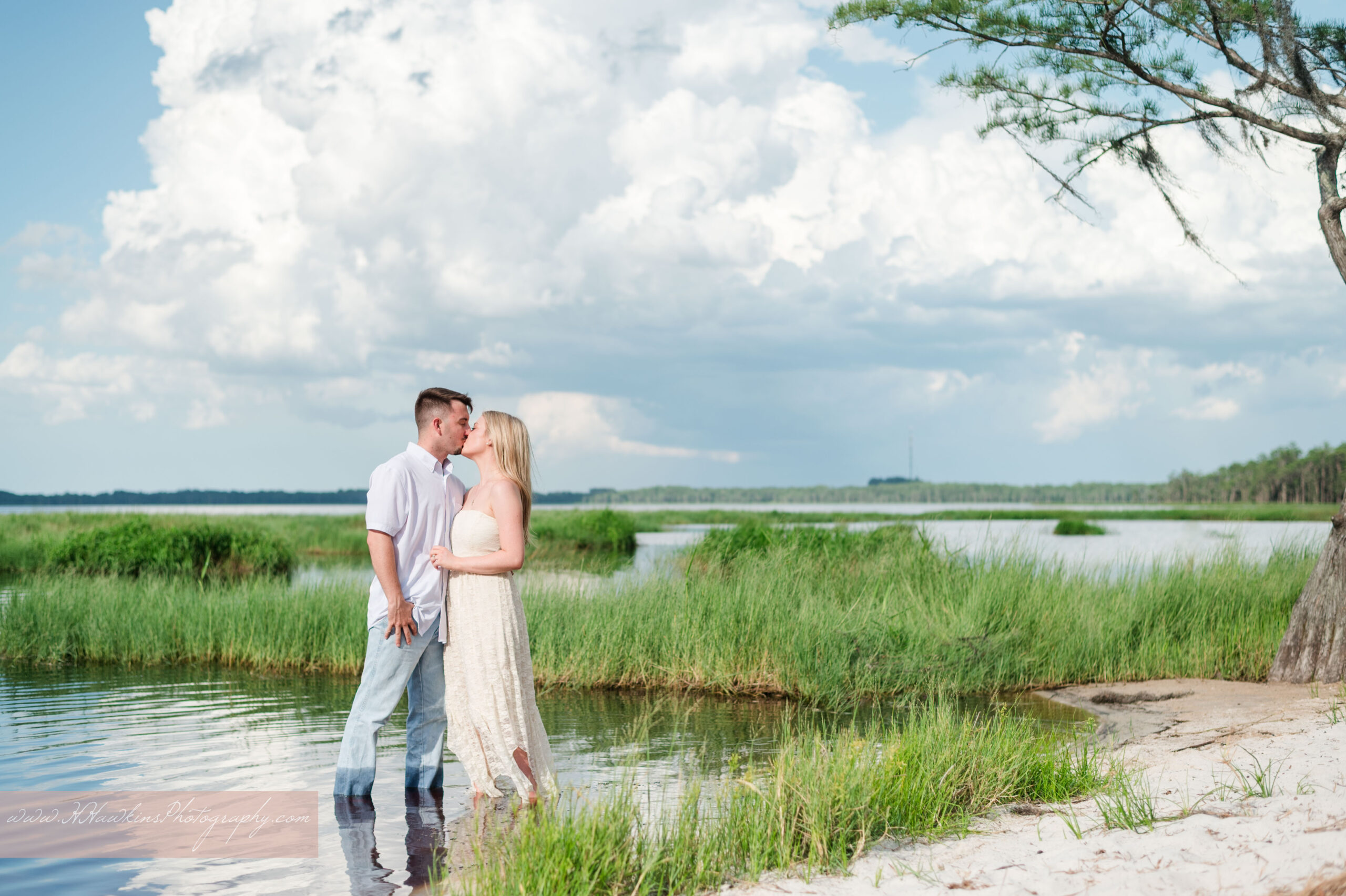 Engaged couple stand in the water near the sandy beach on Lake Louisa for their engagement photos in Clermont FL
